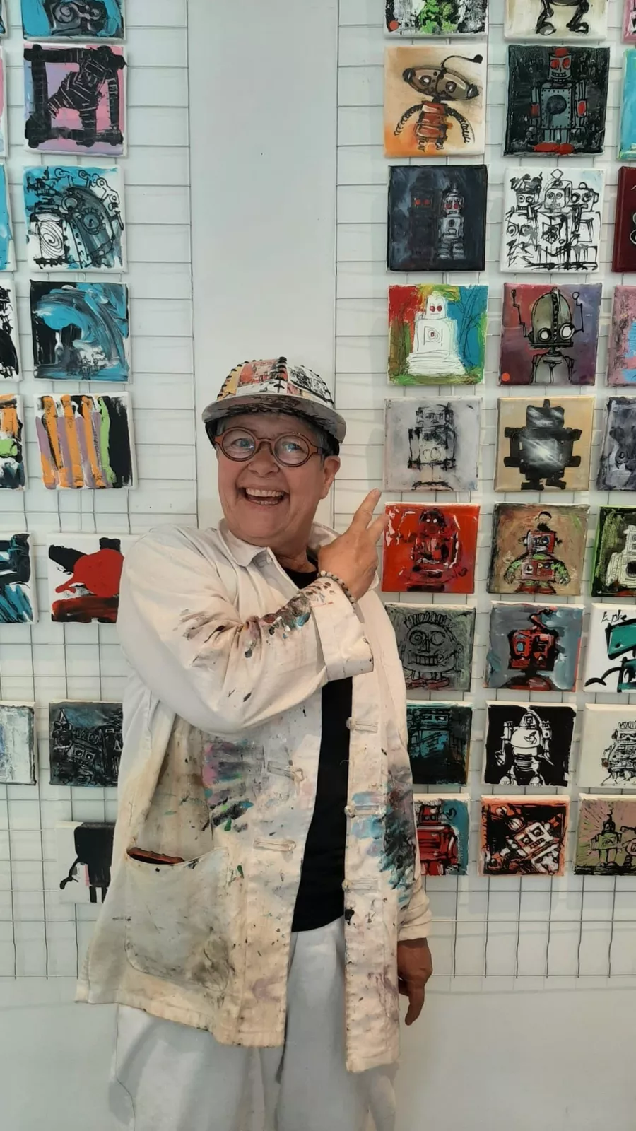 Evelyne Roman dans son atelier, devant un mur de ses petits robots peints